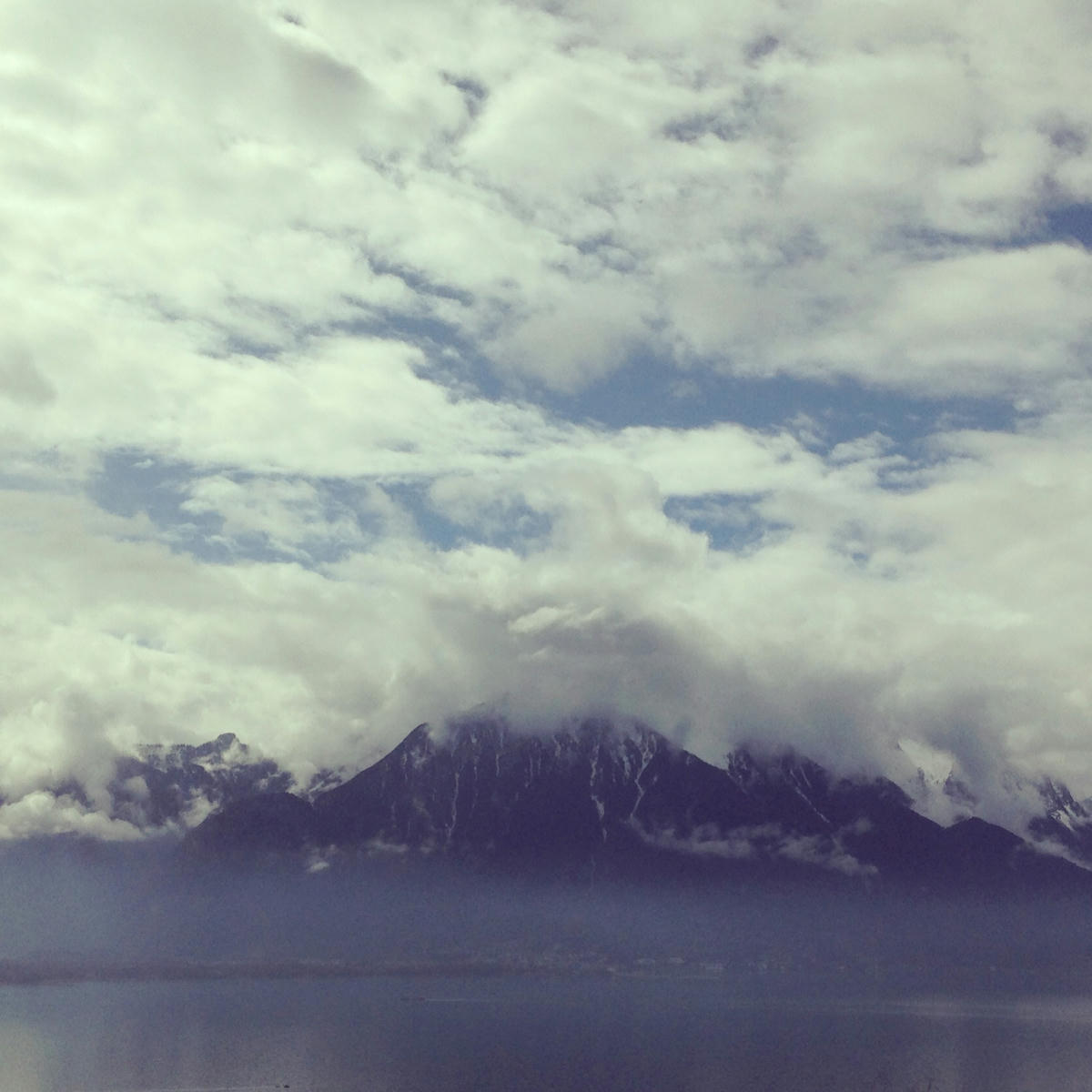 A lake with mountains in the clouds